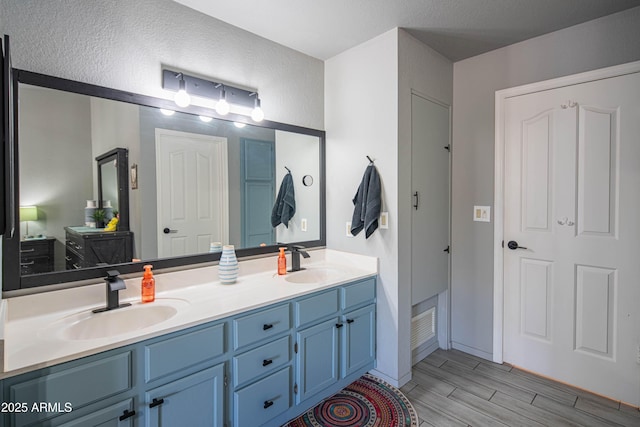 full bathroom with double vanity, wood finish floors, and a sink