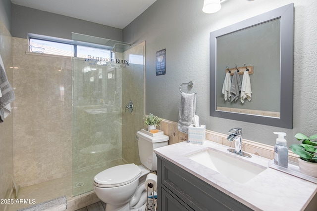 full bath featuring vanity, toilet, a textured wall, and walk in shower