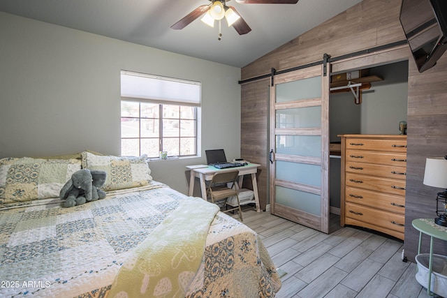 bedroom with a barn door, a ceiling fan, lofted ceiling, and wood tiled floor