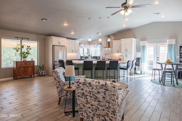 interior space with vaulted ceiling, light wood-style floors, visible vents, and ceiling fan