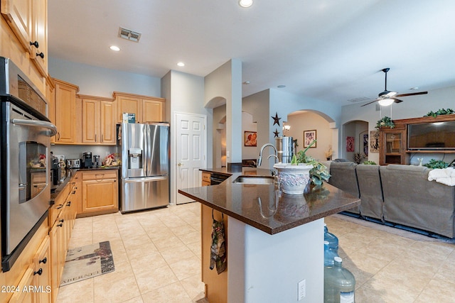 kitchen with a kitchen island with sink, sink, light brown cabinets, ceiling fan, and stainless steel fridge