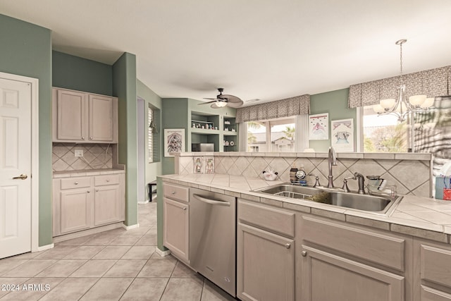 kitchen with sink, stainless steel dishwasher, decorative backsplash, light tile patterned floors, and decorative light fixtures