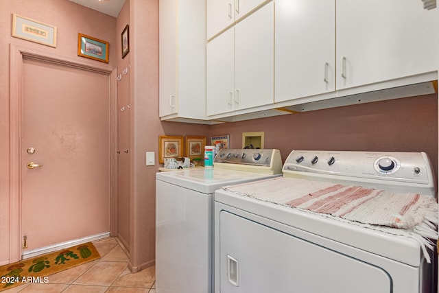 laundry room featuring washing machine and clothes dryer, light tile patterned flooring, and cabinets