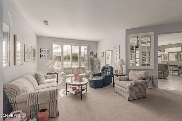 living room featuring light carpet, a textured ceiling, and an inviting chandelier