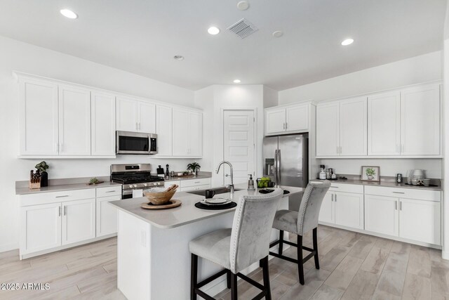 3089 N 200th Ave, Buckeye, AZ 85396 - kitchen with stainless steel appliances, a sink, a kitchen bar, light wood-style flooring, and a kitchen island with sink