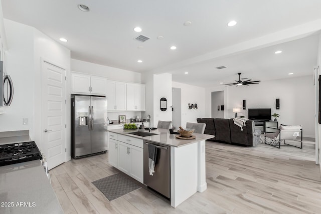 3089 N 200th Ave, Buckeye, AZ 85396 - kitchen with stainless steel appliances, a sink, white cabinetry, ceiling fan, and light wood-type flooring