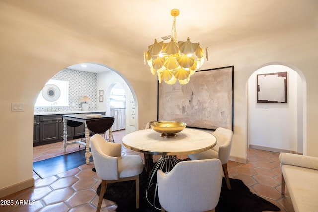 1309 W Lynwood St, Phoenix, AZ 85007 - tiled dining room with arched walkways, a chandelier, baseboards, and a sink
