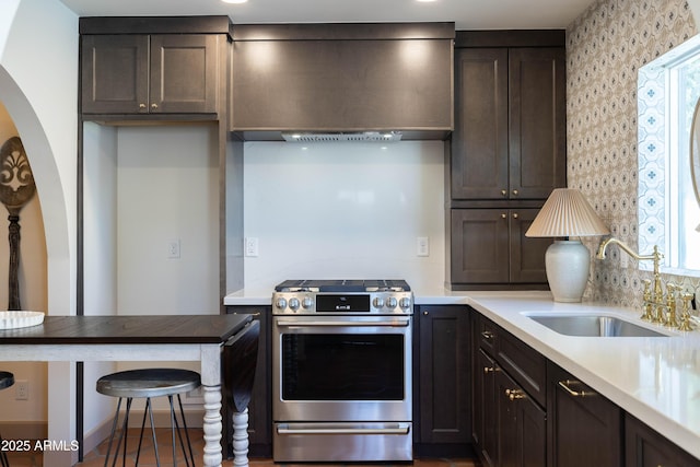 1309 W Lynwood St, Phoenix, AZ 85007 - kitchen featuring stainless steel range with gas cooktop, a sink, arched walkways, light countertops, and dark brown cabinets