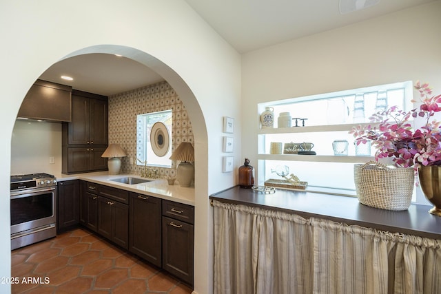 1309 W Lynwood St, Phoenix, AZ 85007 - kitchen featuring stainless steel gas range, a sink, arched walkways, dark tile patterned flooring, and dark brown cabinetry