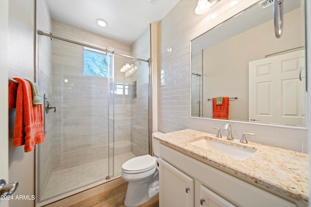 bathroom featuring decorative backsplash, vanity, hardwood / wood-style flooring, a shower with door, and toilet