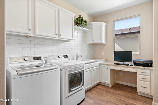 laundry area featuring washing machine and clothes dryer, light hardwood / wood-style floors, cabinets, and sink