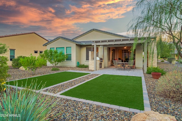 back house at dusk with a lawn and a patio area