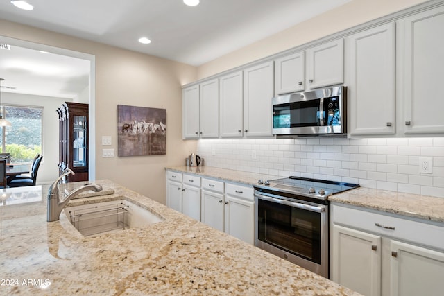 kitchen featuring white cabinetry, light stone counters, tasteful backsplash, stainless steel appliances, and sink