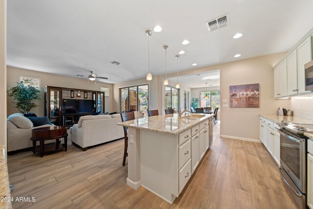 kitchen featuring pendant lighting, a kitchen island with sink, white cabinets, appliances with stainless steel finishes, and ceiling fan