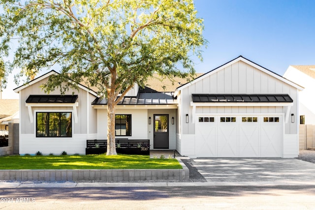 modern farmhouse with metal roof, an attached garage, driveway, board and batten siding, and a standing seam roof