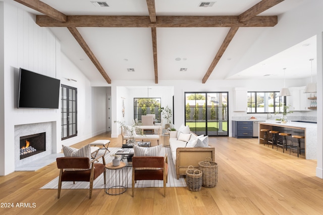 living room featuring light wood-type flooring, beam ceiling, high vaulted ceiling, and a high end fireplace