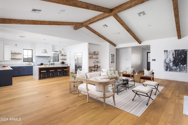 living room featuring vaulted ceiling with beams, light wood-style floors, and visible vents