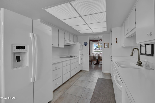 kitchen with light tile patterned flooring, white appliances, white cabinetry, and sink