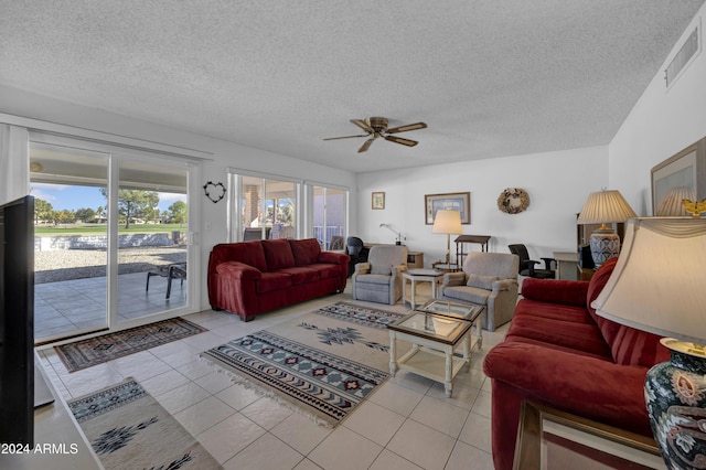 living room featuring ceiling fan, light tile patterned flooring, and a textured ceiling