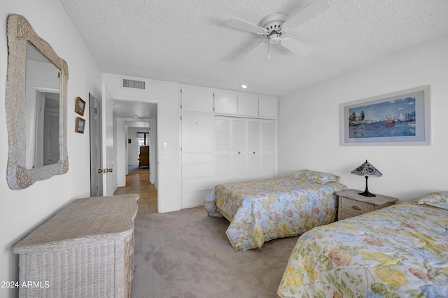 carpeted bedroom featuring a textured ceiling, a closet, and ceiling fan