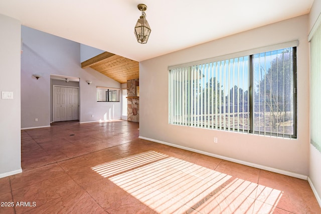 spare room featuring lofted ceiling with beams and baseboards