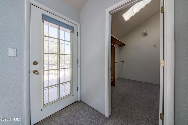 entryway featuring carpet, lofted ceiling, a healthy amount of sunlight, and a textured wall