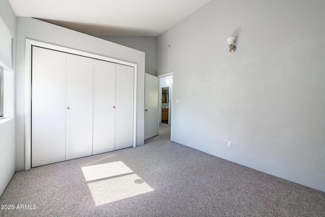 unfurnished bedroom with carpet, a closet, and high vaulted ceiling