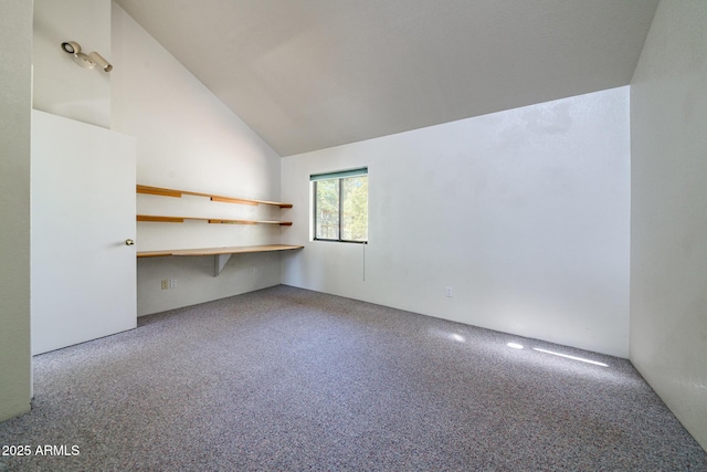 carpeted spare room featuring vaulted ceiling and built in study area