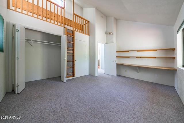 unfurnished bedroom featuring carpet, a closet, and high vaulted ceiling