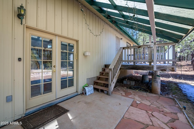 view of exterior entry with a wooden deck, a patio, and french doors