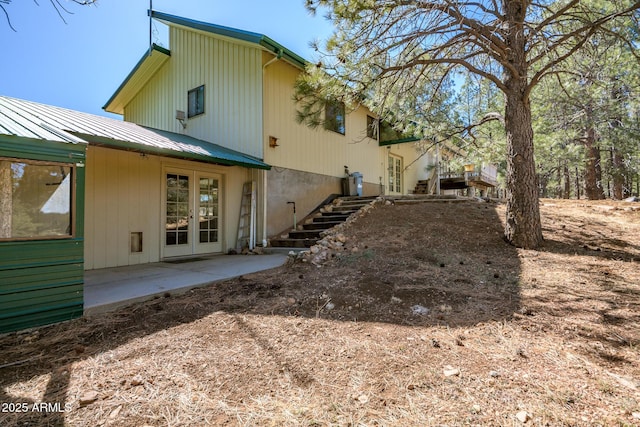 rear view of house featuring stairs, a patio, french doors, and metal roof