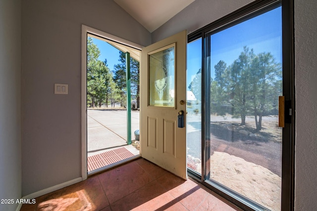 doorway featuring tile patterned floors, baseboards, and lofted ceiling