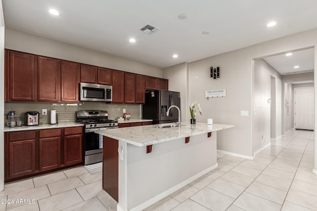 kitchen with tasteful backsplash, a breakfast bar area, an island with sink, sink, and stainless steel appliances