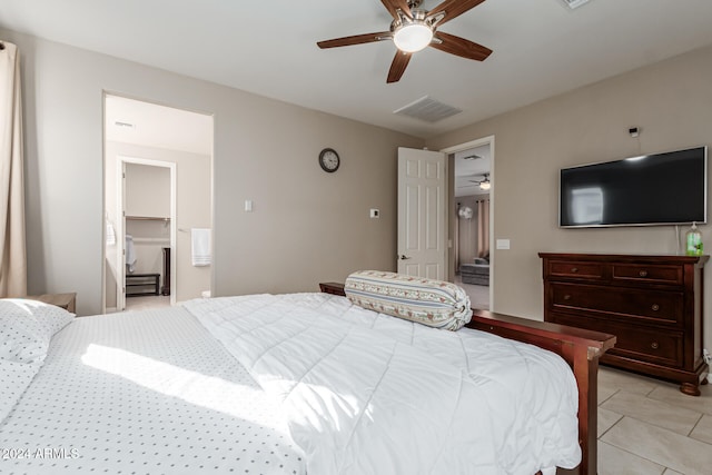 bedroom featuring a spacious closet, light tile patterned flooring, a closet, and ceiling fan