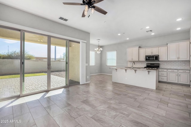 kitchen with pendant lighting, sink, appliances with stainless steel finishes, a kitchen breakfast bar, and white cabinets