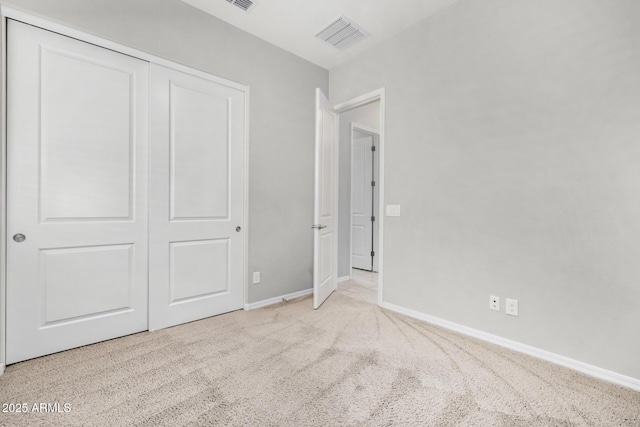 unfurnished bedroom featuring light carpet and a closet