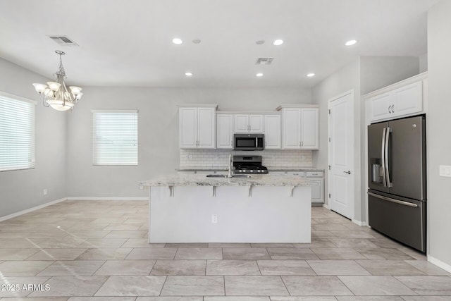 kitchen featuring stainless steel appliances, a kitchen bar, light stone countertops, and white cabinets