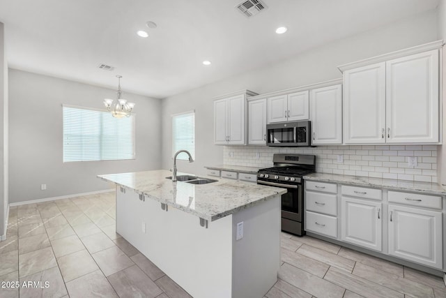 kitchen with sink, stainless steel appliances, white cabinets, and a center island with sink