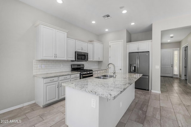 kitchen with sink, white cabinetry, an island with sink, stainless steel appliances, and light stone countertops