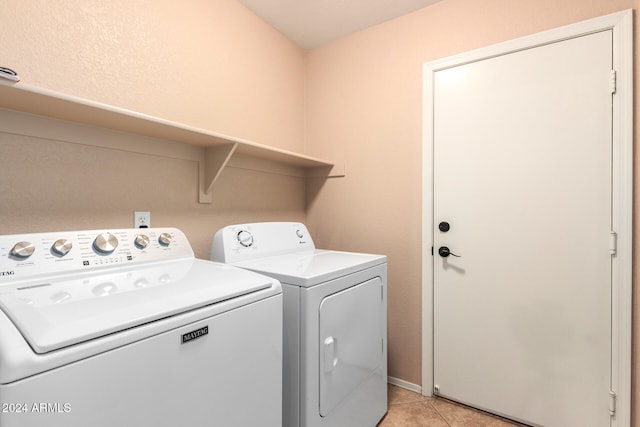 clothes washing area with light tile patterned floors and washer and clothes dryer