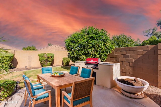 patio terrace at dusk featuring area for grilling