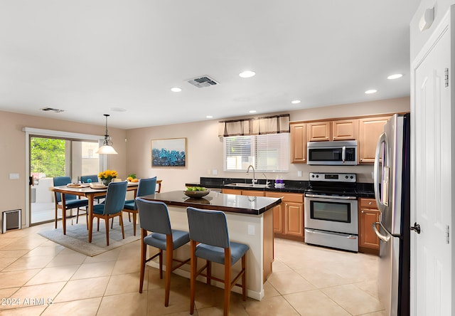 kitchen featuring a breakfast bar area, hanging light fixtures, sink, a center island, and appliances with stainless steel finishes