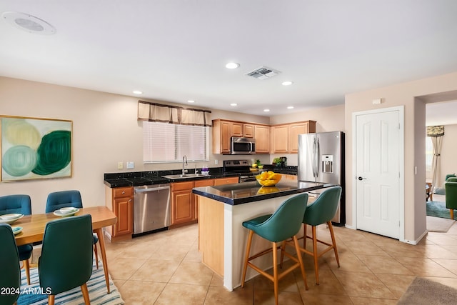 kitchen featuring light tile patterned flooring, appliances with stainless steel finishes, sink, and a kitchen island