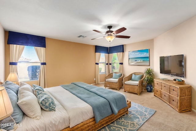 bedroom with ceiling fan, light carpet, and multiple windows