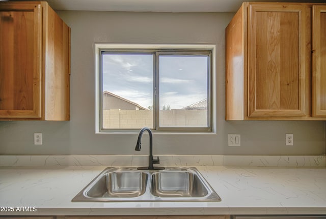 15067 W Taylor St, Goodyear, AZ 85338 - kitchen with a sink, brown cabinetry, and light stone counters