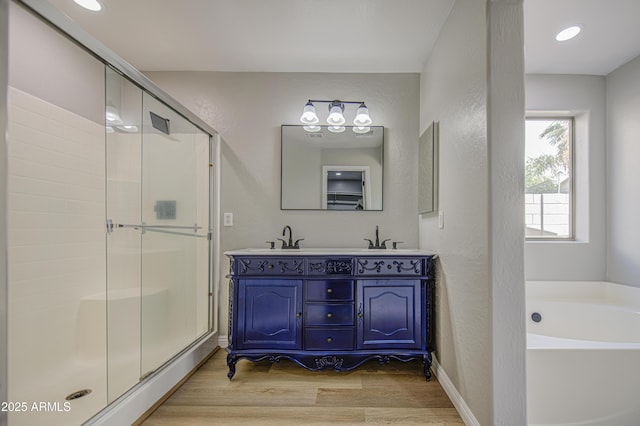 15067 W Taylor St, Goodyear, AZ 85338 - full bath featuring a garden tub, wood finished floors, a stall shower, a textured wall, and double vanity