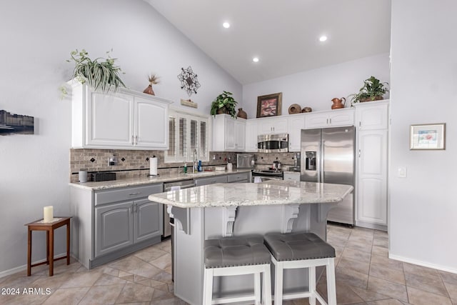 kitchen with decorative backsplash, white cabinetry, a kitchen island, and stainless steel appliances