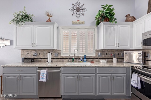 kitchen featuring white cabinetry, sink, backsplash, gray cabinets, and appliances with stainless steel finishes