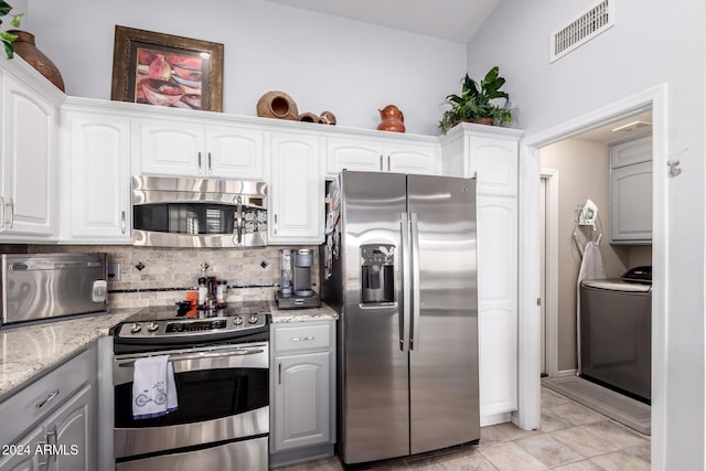 kitchen featuring light stone counters, appliances with stainless steel finishes, tasteful backsplash, washer / dryer, and white cabinetry