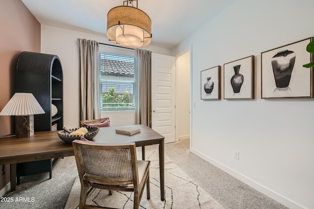 dining room featuring light colored carpet and baseboards